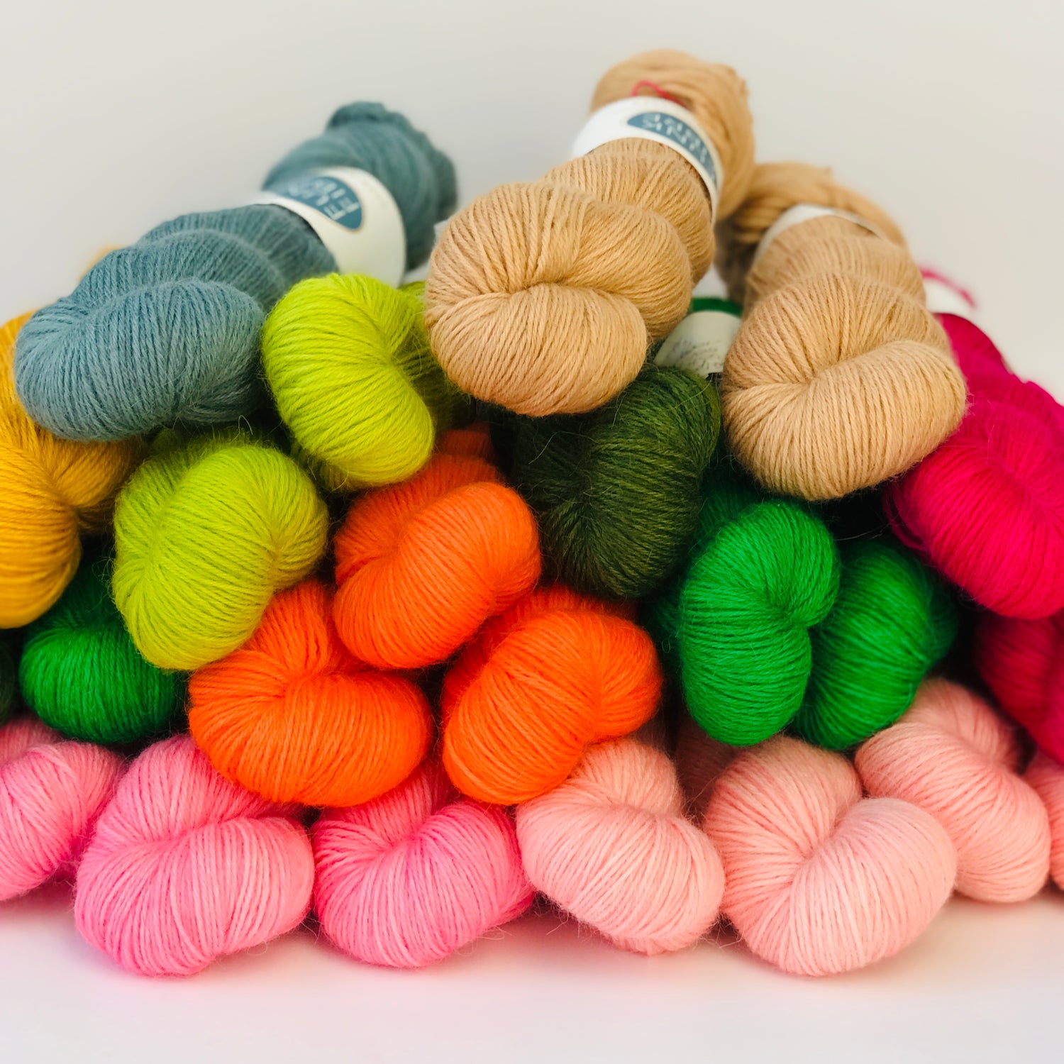 Bunte Stränge Wolle aufgehäuft auf einem Tisch. Orange, gruen, rosa, pink