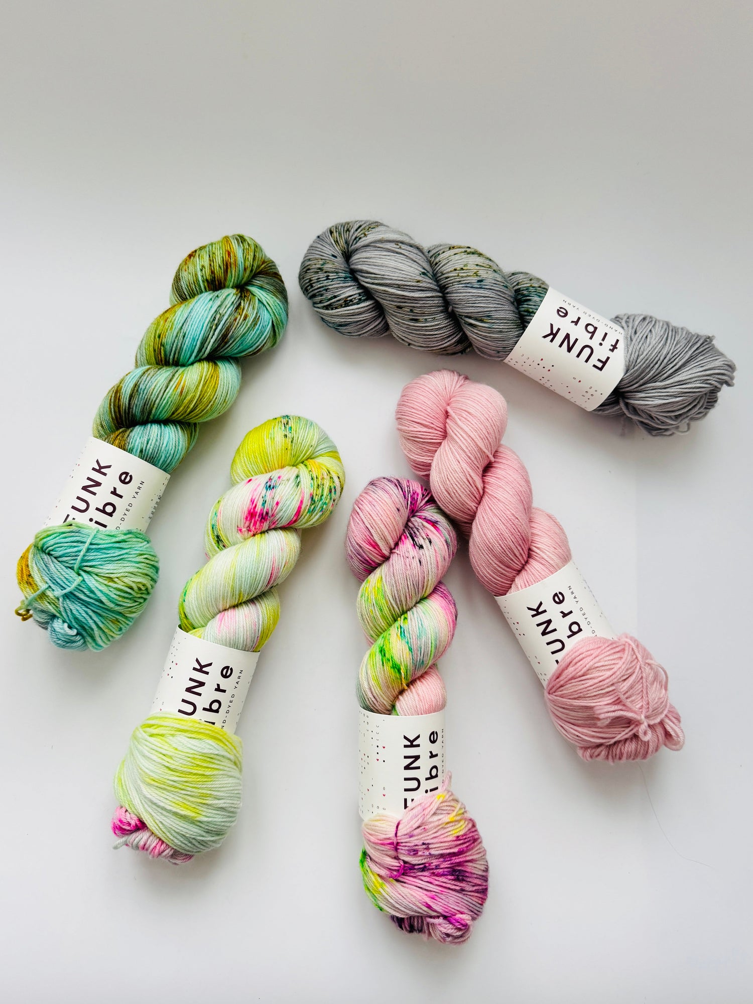 5 Stränge handgefärbte Wolle bunt locker verteilt auf weisser Unterlage